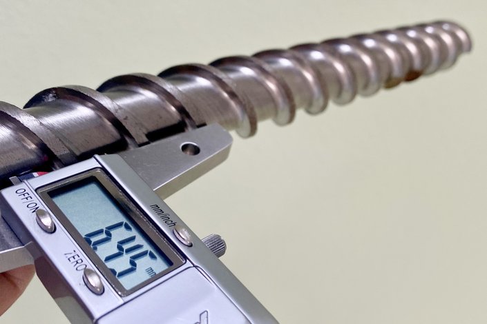 Mit einem Messgerät wird der Verschleiß an einer Extruderschnecke gemessen.